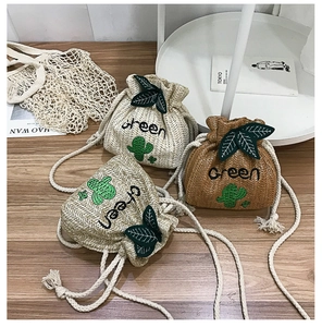 Detail view of woven straw bucket bag featuring Green embroidery and cactus pattern