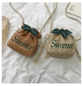 Close-up of woven straw bucket bags with Summer embroidery and green leaf detail