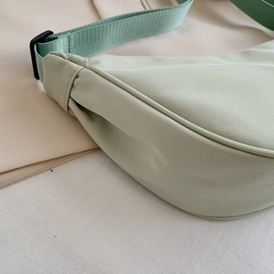 Minimalist mint green nylon crescent bag with adjustable shoulder strap and smooth texture