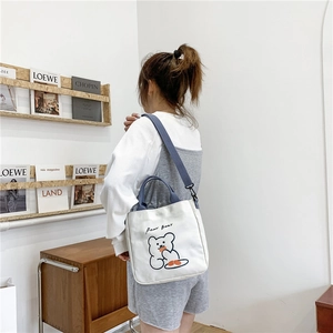 Detail of cute bear canvas tote bag with blue straps and shoulder strap on model
