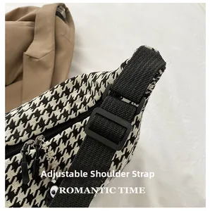 Detail of adjustable black nylon strap on a houndstooth crossbody bag with buckle