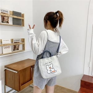 Detail of white canvas tote bag with cute cartoon bear print and grey shoulder straps