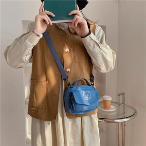 Close-up of blue canvas crossbody bag with cute cartoon bear embroidery and strap