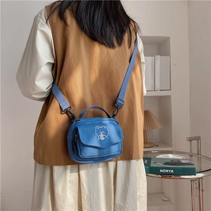 Detail of blue canvas mini square bag featuring a cute cartoon bear print and strap