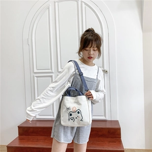 Close-up of white canvas bag featuring a cute cartoon bear print and blue fabric handles