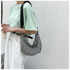 Detail of black and white houndstooth pattern crossbody bag with wide canvas strap