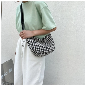 Detail of checkered crossbody bag with adjustable wide strap shown on a model