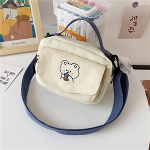 Detail of cute bear embroidery and front zipper pocket on white canvas crossbody bag