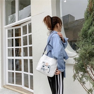 Detail shot of the white canvas shoulder bag featuring a cute bear print and blue strap