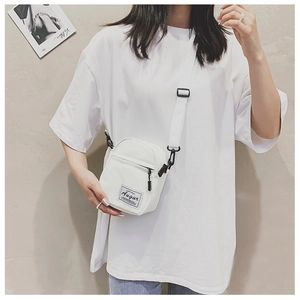 Detail view of mini white canvas crossbody bag featuring adjustable strap and black zipper