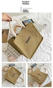 Detail of yellow canvas tote bag featuring black merci print and white rope handles