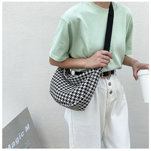 Detail of checkered crossbody bag with black and white houndstooth pattern on wide strap