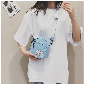 Mini light blue canvas crossbody bag with Augur label shown on a model