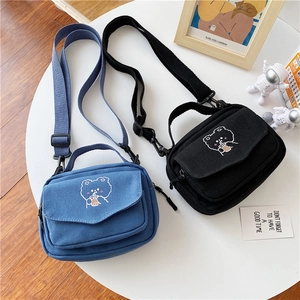 Detail of cute bear embroidery on durable canvas crossbody bags in blue and black colors