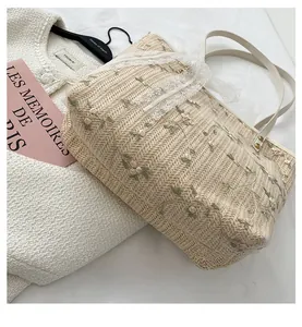 Detail of floral embroidery and delicate lace trim on a woven straw tote bag