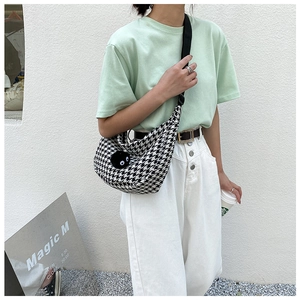 Detail of checkered half-moon crossbody bag with plush charm and adjustable strap