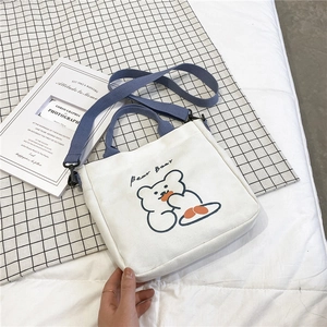 Detail of white canvas tote bag with blue handles and cute cartoon bear print