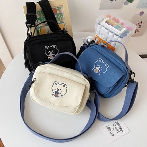 Detailed close-up of colorful canvas crossbody bags with cute cartoon bear embroidery
