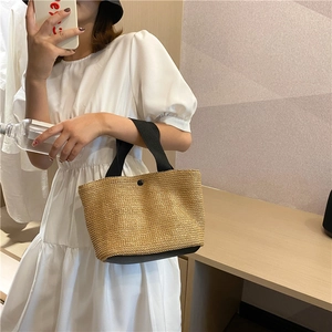Detail der handgewebten Strohstrandtasche mit schwarzen Griffen und Naturtextur
