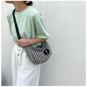 Detail showing checkered half-moon crossbody bag with a cute black plush mascot charm