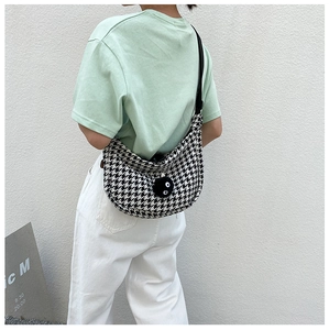 Detail of checkered crossbody bag with black plush charm and wide fabric shoulder strap