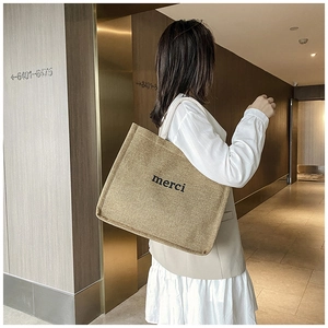 Close-up of a minimalist linen tote bag with merci print for casual daily styling