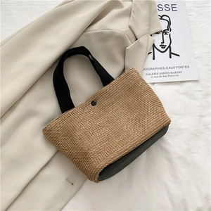 Detail der gewebten Strohtasche mit schwarzem Lederboden und dicken Stoffgriffen