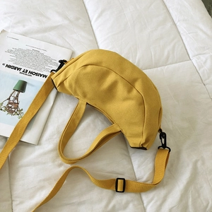 Sac à main croissant en toile jaune avec bandoulière sur un fond blanc matelassé