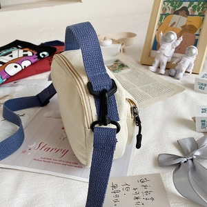 Cute off-white canvas crossbody bag with blue strap for women in a casual lifestyle setting