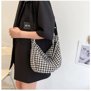 Classic black and white houndstooth crescent bag shown on model in a minimalist setting