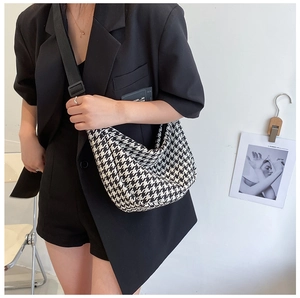 Detail of black and white houndstooth pattern fabric on a crescent shaped crossbody bag