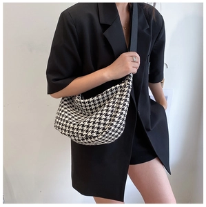 Close-up of black and white houndstooth crossbody bag featuring a half-moon crescent shape