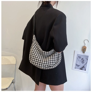 Detailed back-view of a black and white houndstooth half-moon crossbody bag on a model