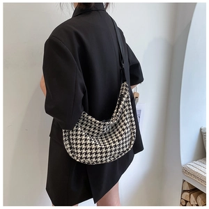 Detail of a black and white houndstooth hobo crossbody bag styled on a model in a black blazer
