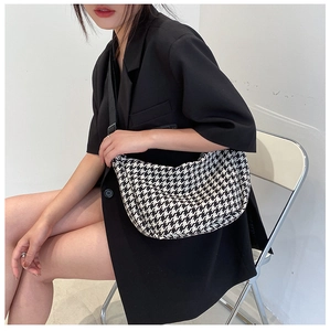 Detail of black and white houndstooth crossbody bag with adjustable shoulder strap