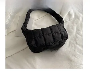 Detail view of black quilted puff shoulder bag with waterproof nylon texture and stitching