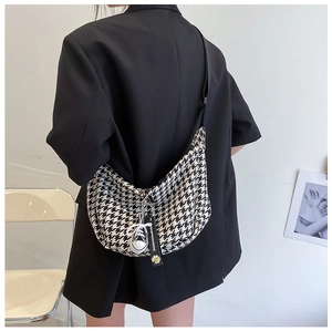 Detail of checkered crescent crossbody bag with daisy charm and adjustable strap