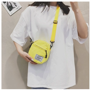 Detailed close-up of a mini yellow canvas crossbody bag with white Augur logo tag