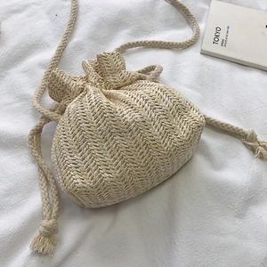 Handwoven straw bucket bag with drawstring closure and slim shoulder strap for summer beach vacation