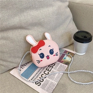 Close-up of pink cartoon rabbit shoulder bag with red bow on a vintage newspaper background