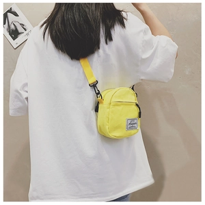 Mini yellow canvas crossbody bag shown on a model's back to demonstrate size and style