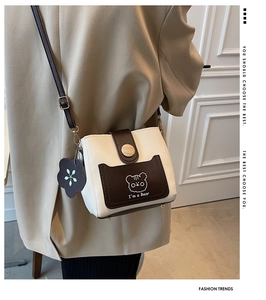 Detail of mini bucket bag showing contrast colors, bear print, and floral charm accessory