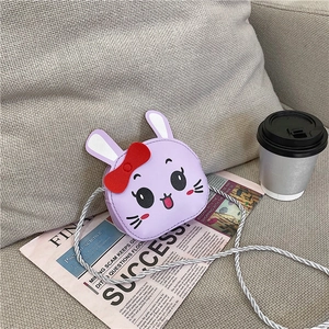 Detail of cute purple rabbit shoulder bag for kids with bow and woven strap on newspaper