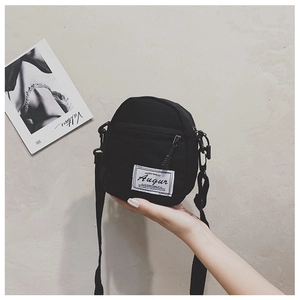 Detailed shot of black canvas crossbody bag with white woven label and adjustable strap