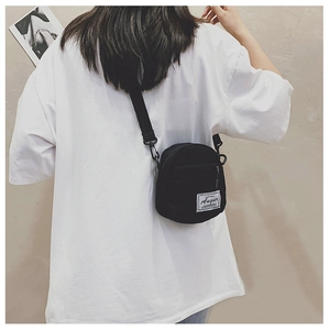 Rear view of a black canvas crossbody bag on a model showing compact size and fit