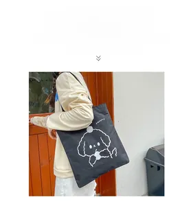 Close-up of black canvas tote bag featuring a white cartoon dog print and Yammy text