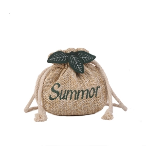 Straw woven bucket bag with Summer embroidery and green leaf accents for beach style