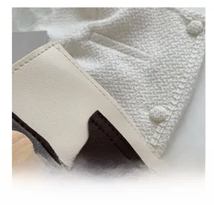 Detail of color-block bucket bag with precision stitching and wooden button accent
