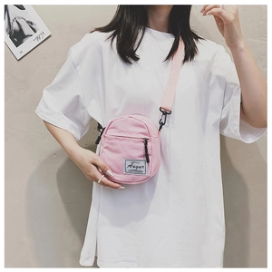 Detail of pink canvas crossbody bag with adjustable strap and black metal hardware