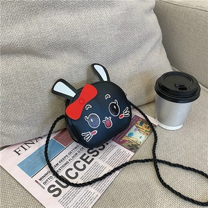 Detail view of mini round black cartoon crossbody bag with white rabbit ears and red bow
